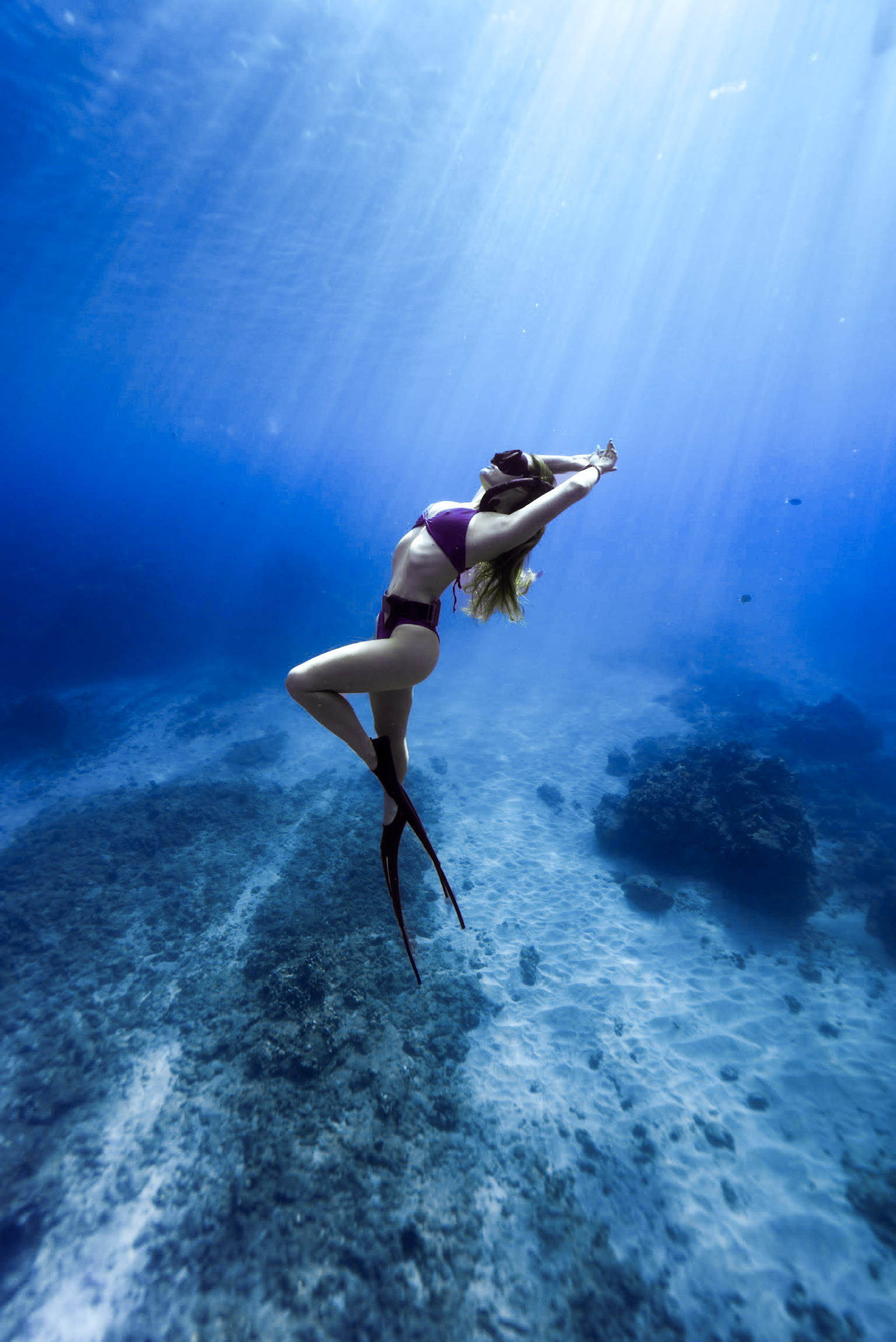 A freediver rising through sunlit blue water