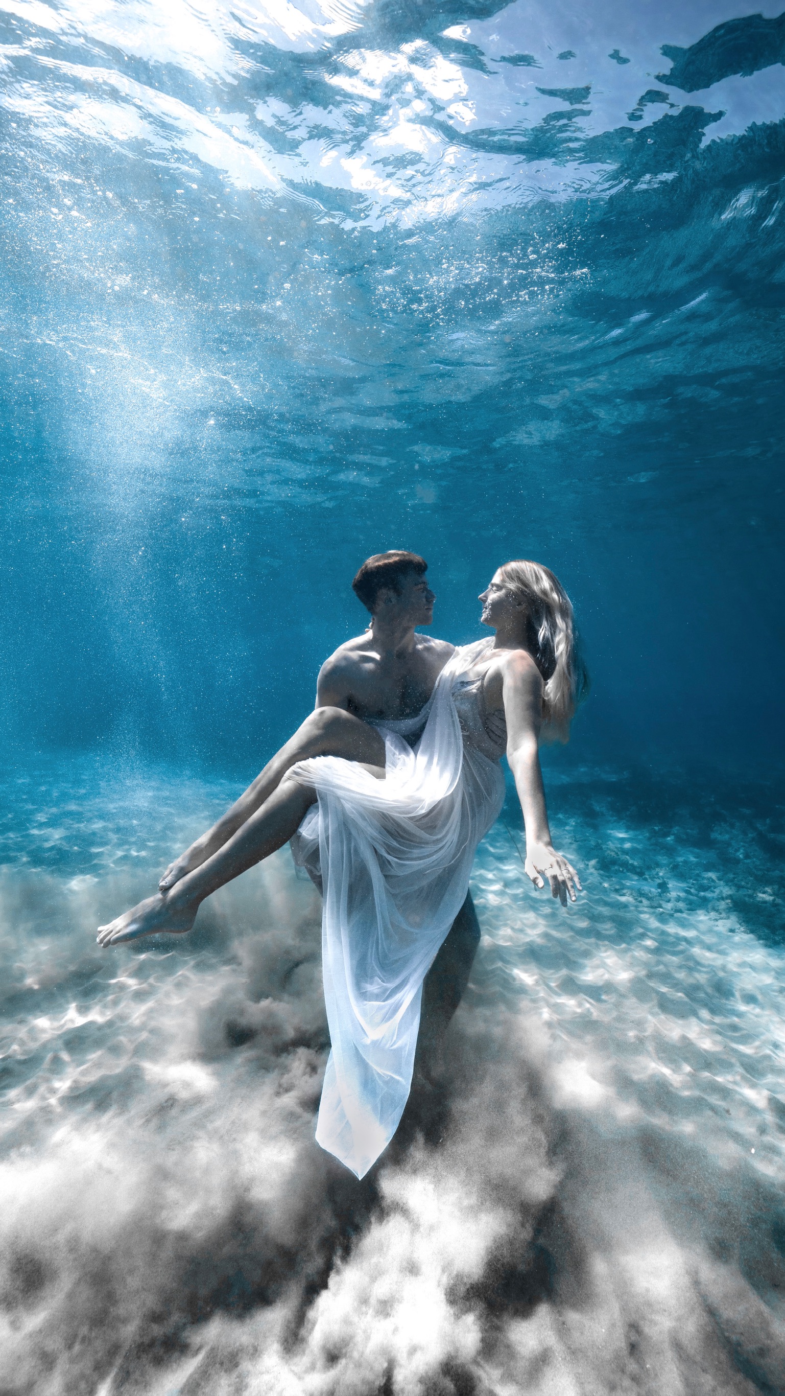 A couple underwater, she in a flowing white dress